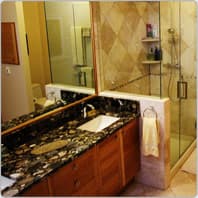 Remodeled master bathroom with black granite counters and a glass shower